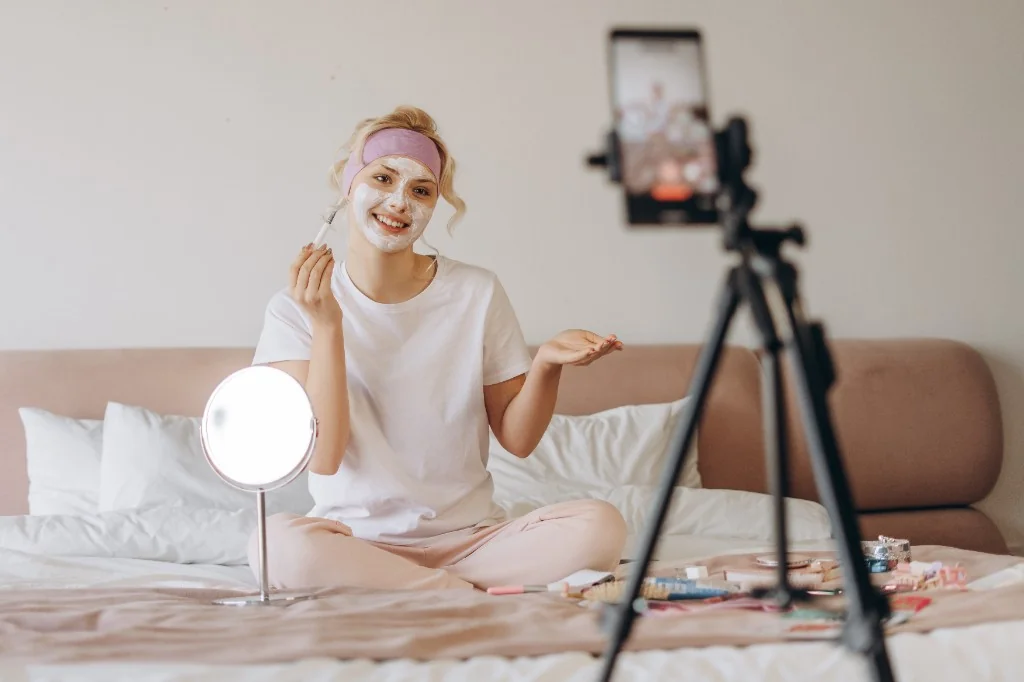Créatrice filmant un tutoriel beauté sur smartphone, chambre lumineuse, collaboration contenu marque